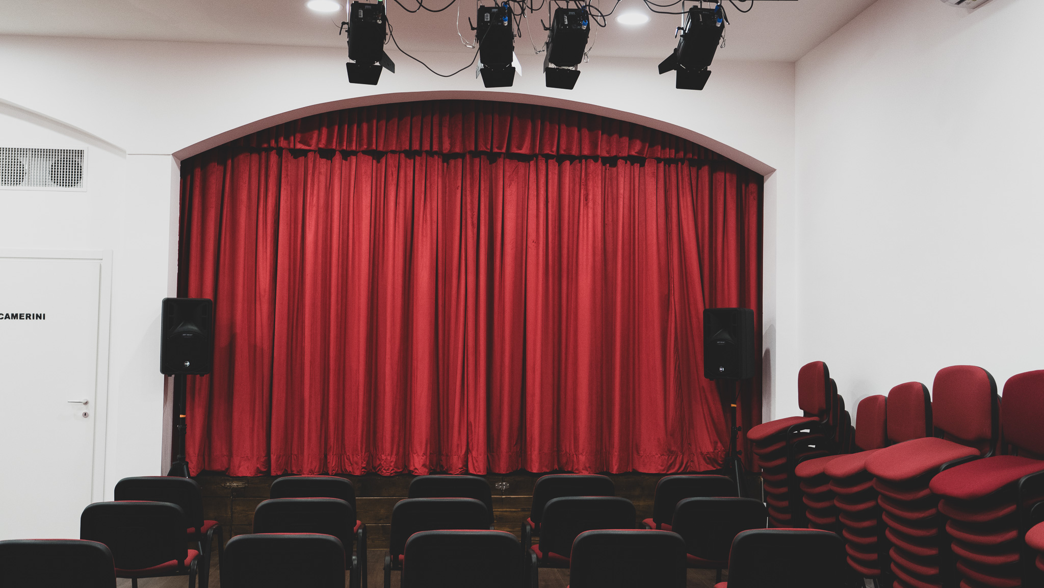 Il sipario rosso, i fari di sala e le sedie di velluto rosso del Teatro degli Audaci Off